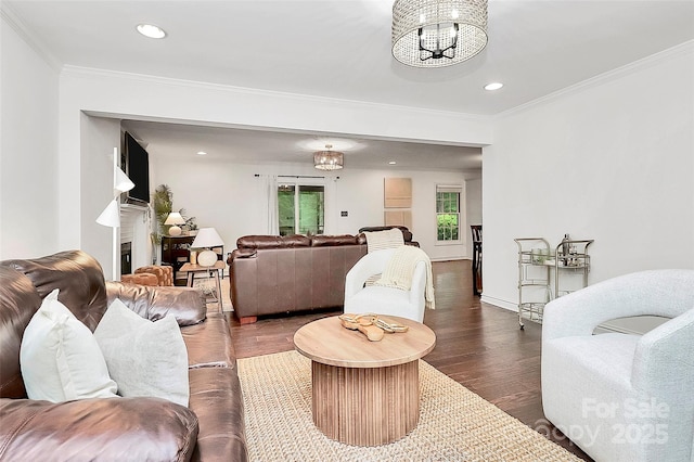 living room featuring recessed lighting, an inviting chandelier, ornamental molding, and wood finished floors