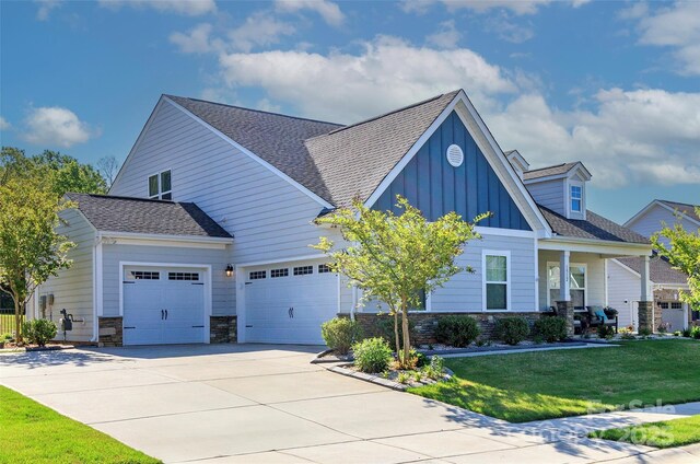 1512 Brooksland Pl, Waxhaw, NC 28173 - view of front facade with board and batten siding, an attached garage, concrete driveway, stone siding, and a front lawn