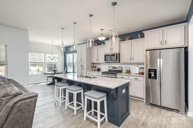 1512 Brooksland Pl, Waxhaw, NC 28173 - kitchen featuring appliances with stainless steel finishes, a sink, open floor plan, light wood-style floors, and decorative backsplash
