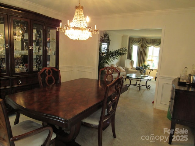 dining space with a wainscoted wall, ornamental molding, a decorative wall, and a notable chandelier