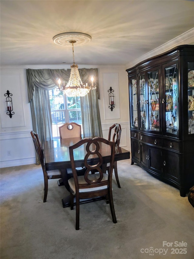 dining space with light colored carpet, a notable chandelier, ornamental molding, and a decorative wall