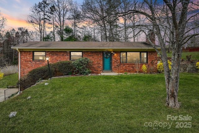 ranch-style house with a front lawn, a chimney, fence, and brick siding