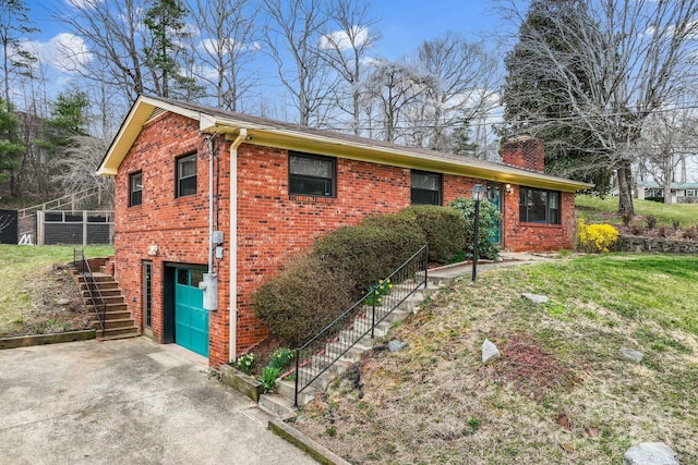 exterior space with stairs, an attached garage, driveway, brick siding, and a chimney