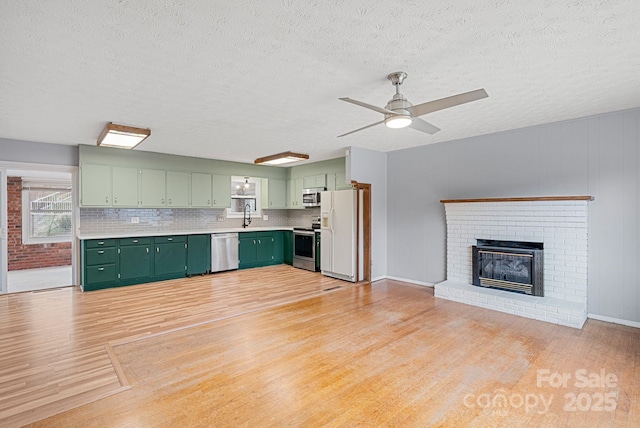 kitchen with light wood finished floors, green cabinets, light countertops, and appliances with stainless steel finishes
