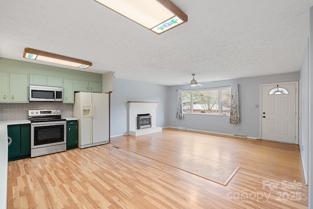 kitchen featuring light countertops, light wood-style flooring, stainless steel appliances, ceiling fan, and green cabinetry