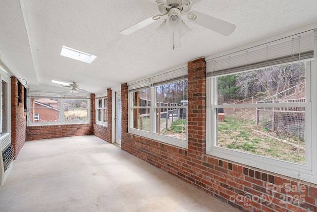 unfurnished sunroom with a ceiling fan and a skylight