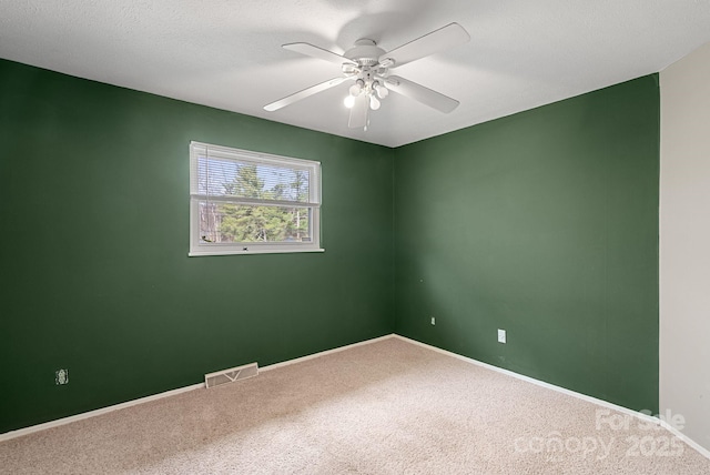 carpeted empty room featuring baseboards, a textured ceiling, visible vents, and a ceiling fan