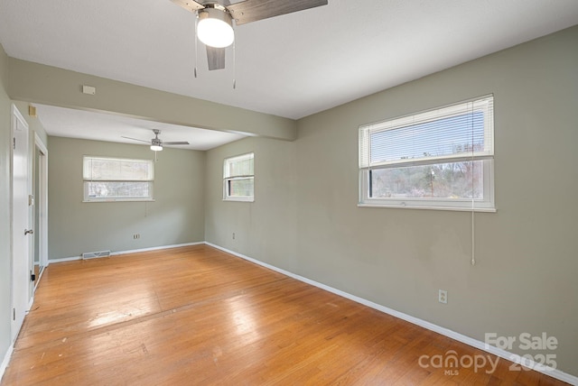 unfurnished room featuring baseboards, visible vents, light wood-style floors, and a ceiling fan
