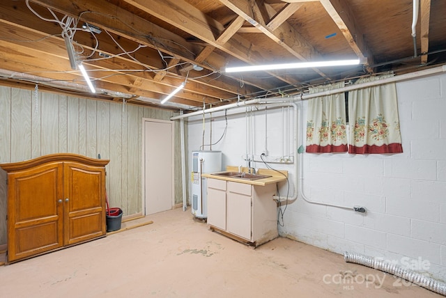 unfinished basement with a sink, concrete block wall, and electric water heater