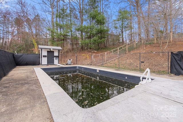 view of pool featuring an outbuilding, a storage unit, and fence