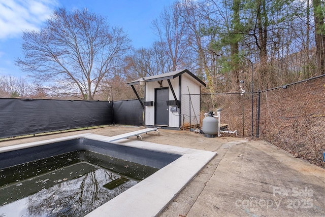 view of swimming pool with a diving board, a fenced backyard, an outbuilding, and a shed