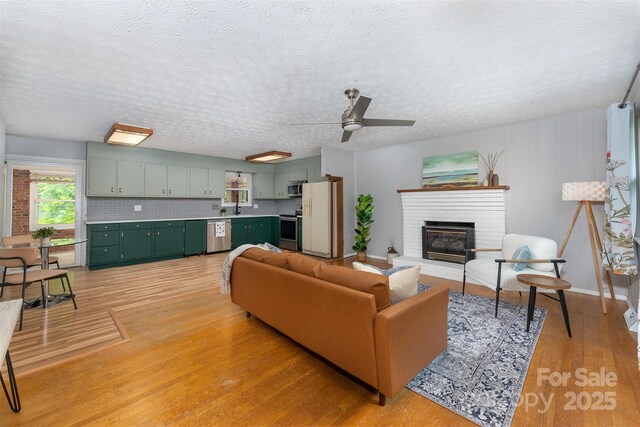 31 Vista Dr, Candler, NC 28715 - living area with light wood finished floors, a textured ceiling, ceiling fan, a fireplace, and baseboards
