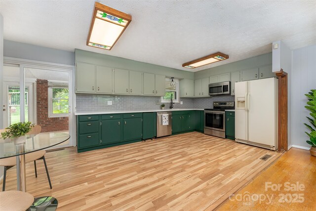 31 Vista Dr, Candler, NC 28715 - kitchen featuring stainless steel appliances, green cabinetry, healthy amount of natural light, a sink, and a textured ceiling