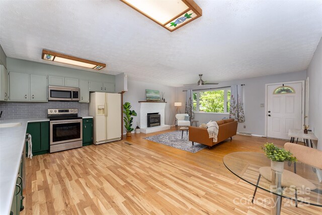 31 Vista Dr, Candler, NC 28715 - living room featuring a fireplace, light wood-style flooring, ceiling fan, baseboards, and a textured ceiling