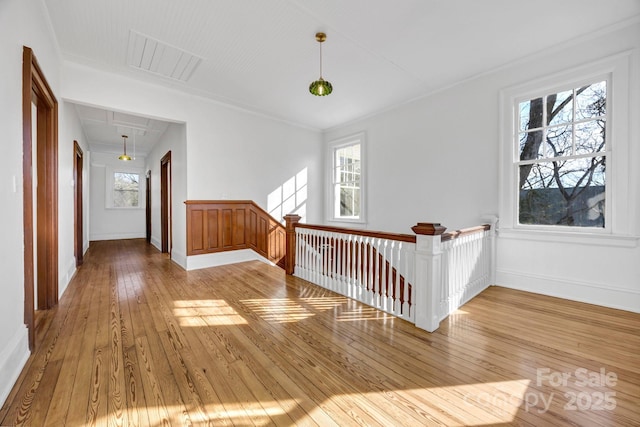 hallway featuring visible vents, baseboards, attic access, hardwood / wood-style flooring, and an upstairs landing