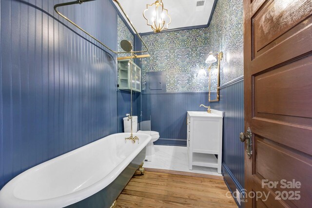 full bathroom featuring vanity, wood finished floors, a soaking tub, an inviting chandelier, and wainscoting