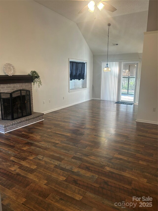 unfurnished living room featuring dark wood finished floors, a fireplace, baseboards, and a ceiling fan