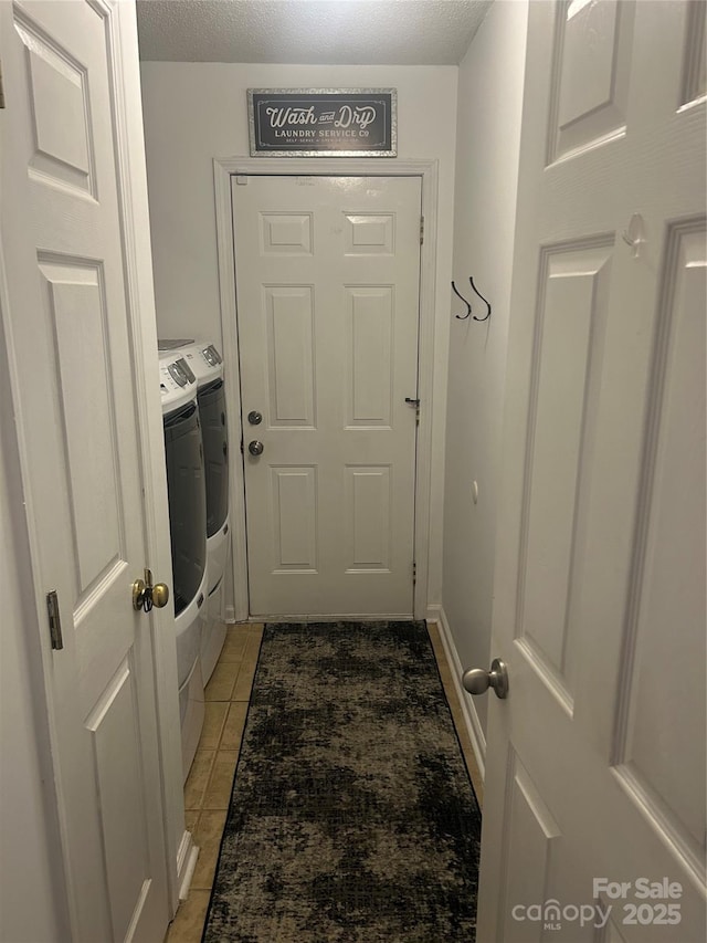 entryway with a textured ceiling, washing machine and dryer, and light tile patterned flooring