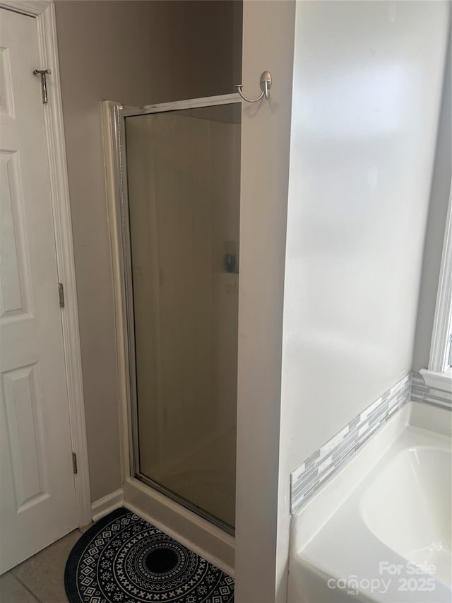 full bath featuring tile patterned flooring, a garden tub, and a stall shower