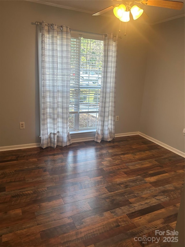 spare room featuring dark wood-style floors, baseboards, crown molding, and a ceiling fan