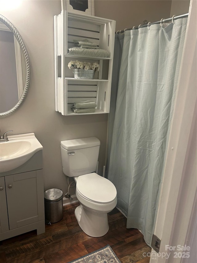 bathroom featuring curtained shower, toilet, wood finished floors, and vanity