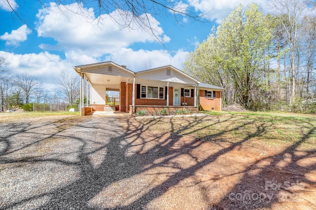 view of front facade featuring gravel driveway, a carport, a porch, and brick siding