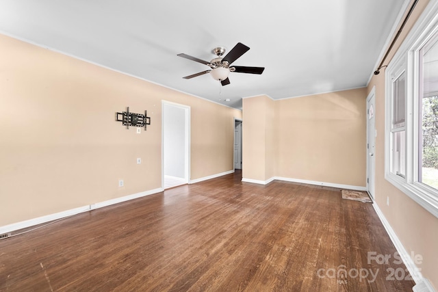 spare room with wood finished floors, a ceiling fan, and baseboards