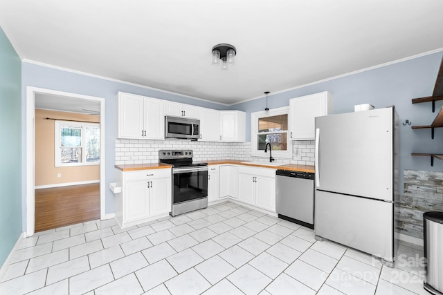 kitchen with a sink, white cabinets, appliances with stainless steel finishes, and butcher block counters