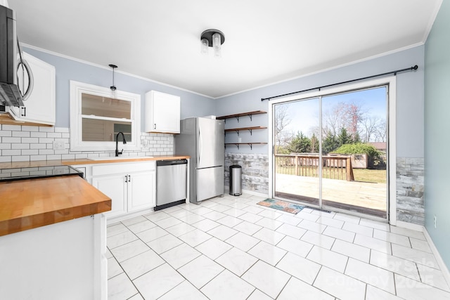 kitchen with crown molding, stainless steel appliances, wood counters, and a sink