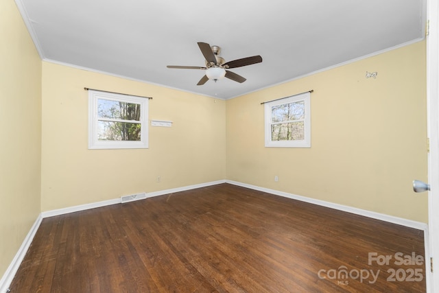spare room featuring a ceiling fan, visible vents, baseboards, dark wood-style flooring, and crown molding