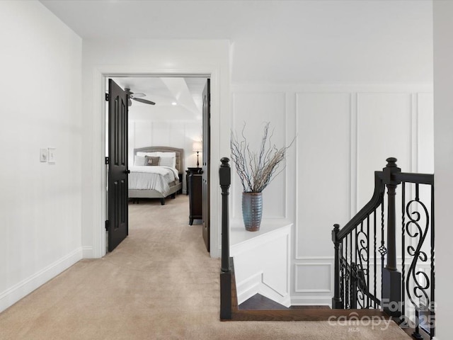 604 Wisteria Walk Way, Fort Mill, SC 29715 - hallway with a decorative wall, an upstairs landing, light carpet, wainscoting, and baseboards