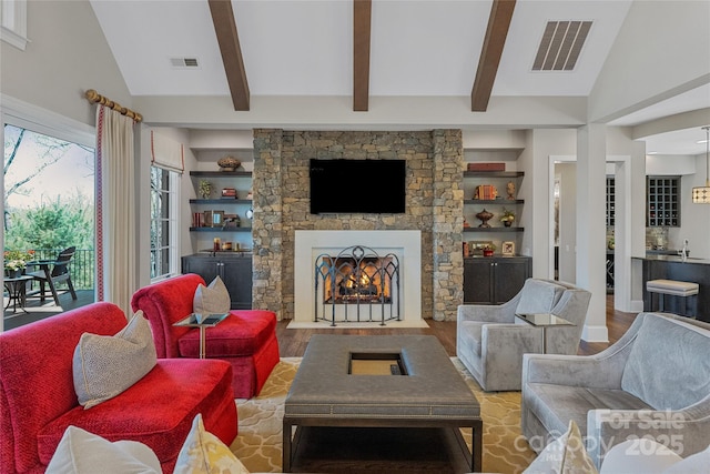 349 Stoneledge Trl, Arden, NC 28704 - living room featuring visible vents, a stone fireplace, vaulted ceiling with beams, and wood finished floors