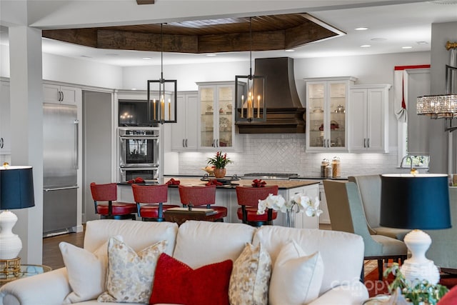 349 Stoneledge Trl, Arden, NC 28704 - kitchen with decorative light fixtures, a notable chandelier, stainless steel appliances, custom range hood, and decorative backsplash