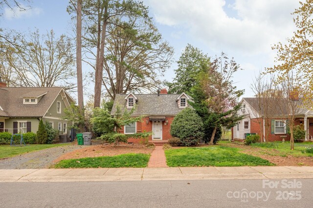 view of front of house with brick siding, driveway, a chimney, and a front lawn