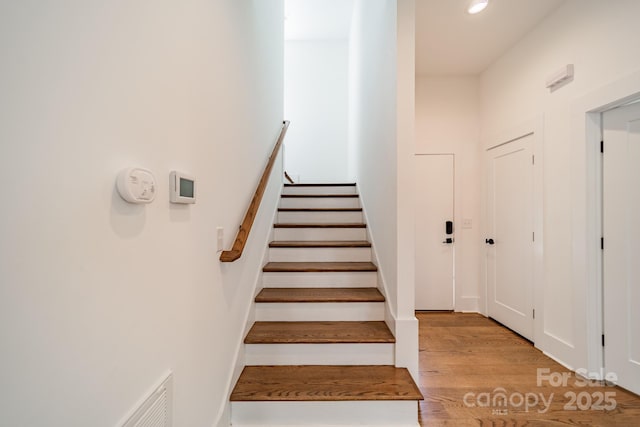 stairway featuring visible vents, wood finished floors, and recessed lighting