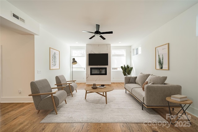 living room featuring wood finished floors, baseboards, ceiling fan, and visible vents