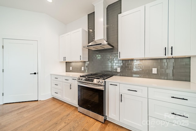 kitchen featuring light countertops, gas stove, light wood-style floors, white cabinets, and wall chimney exhaust hood