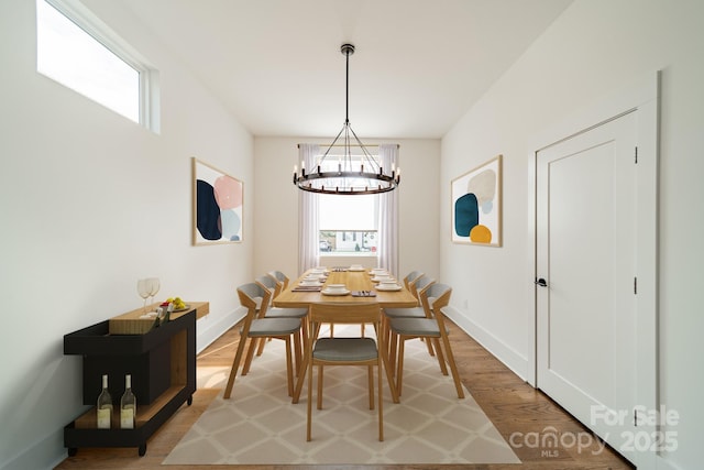 dining room featuring baseboards, light wood-style flooring, and an inviting chandelier