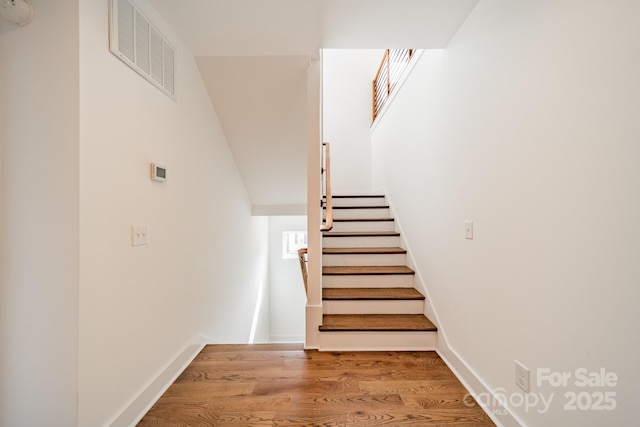 stairway featuring wood finished floors and visible vents