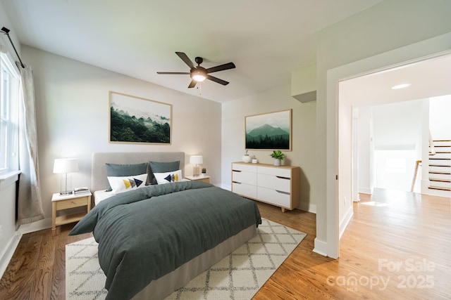 bedroom featuring baseboards, wood finished floors, and a ceiling fan