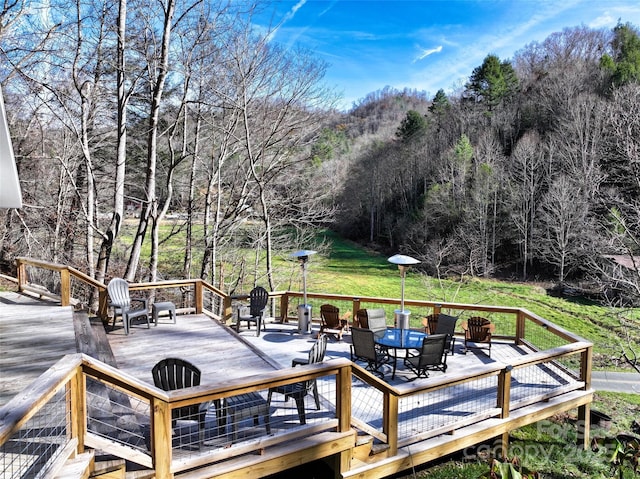 wooden terrace featuring a fire pit and a view of trees