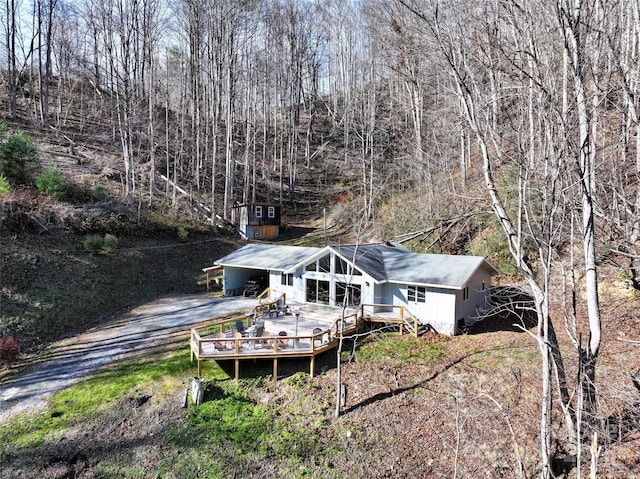 back of property featuring driveway, a wooden deck, and an attached carport