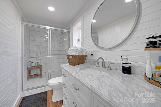 full bathroom with toilet, a stall shower, vanity, and wood finished floors