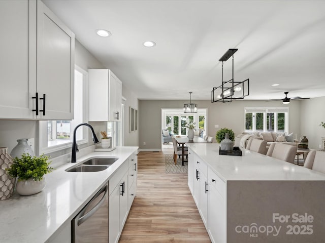 kitchen with a sink, stainless steel dishwasher, light wood-style flooring, decorative light fixtures, and ceiling fan