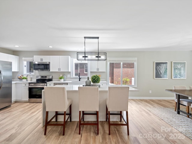 kitchen featuring a breakfast bar area, light countertops, a sink, and stainless steel appliances