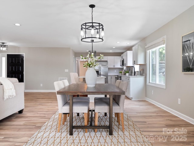 dining area with baseboards, a notable chandelier, light wood-style flooring, and recessed lighting