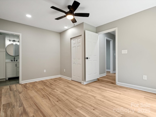 unfurnished bedroom with baseboards, ensuite bath, light wood-style flooring, and a sink