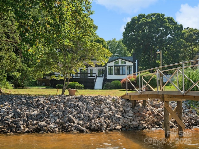 view of dock with a lawn, stairs, and a water view