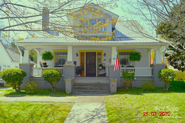 view of front of property with metal roof, a standing seam roof, a porch, and a front yard