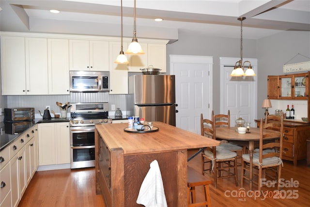 kitchen with wood finished floors, butcher block countertops, stainless steel appliances, and a kitchen island